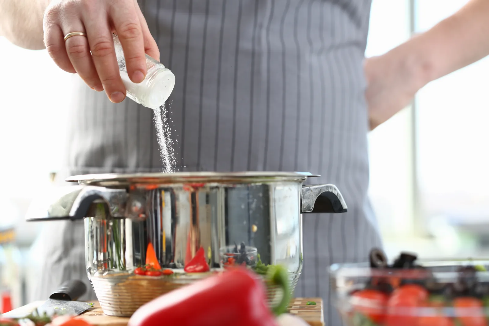 Chef adding salt to a metal cooking pot