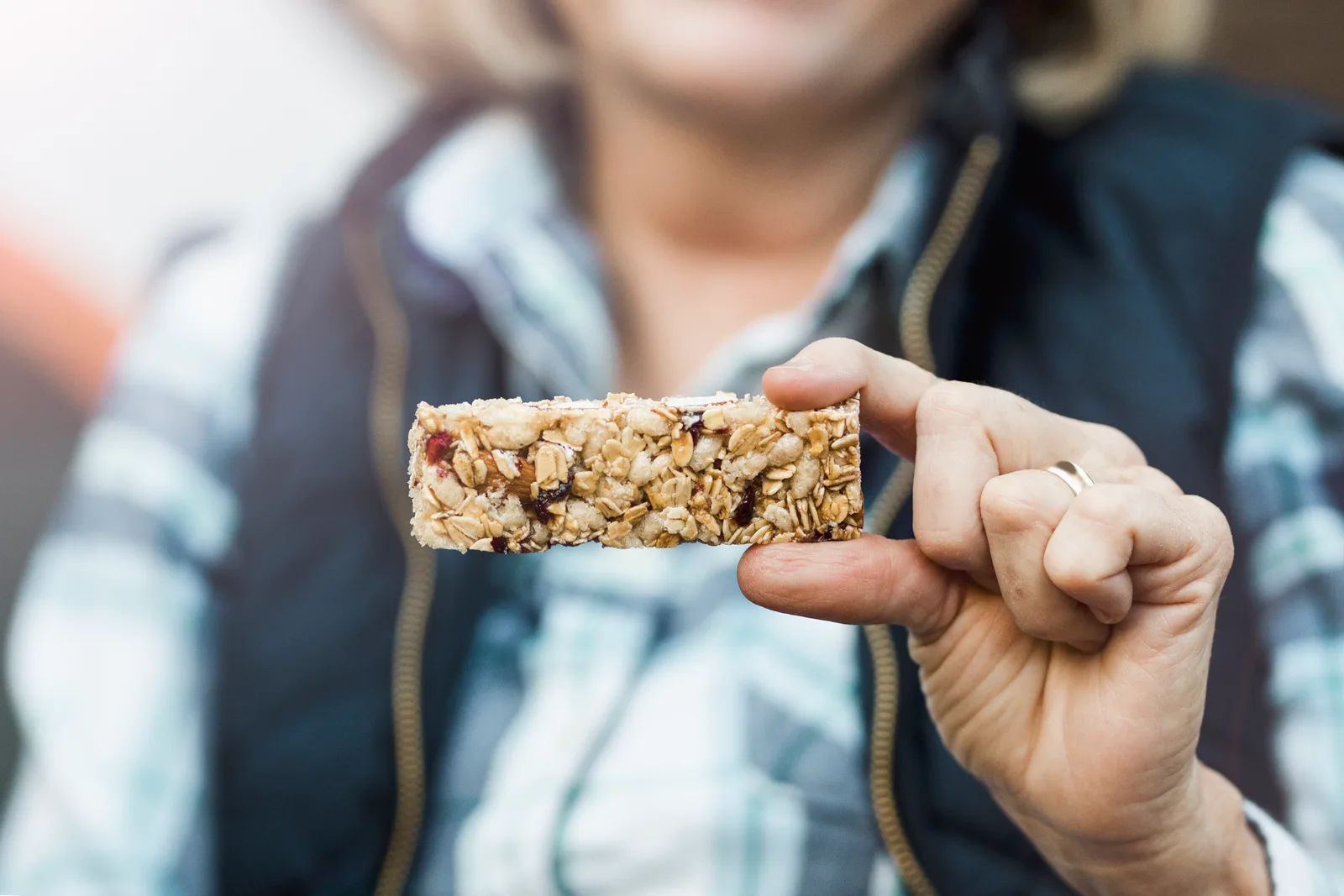 A lady holding a protein bar made with seeds and nuts.