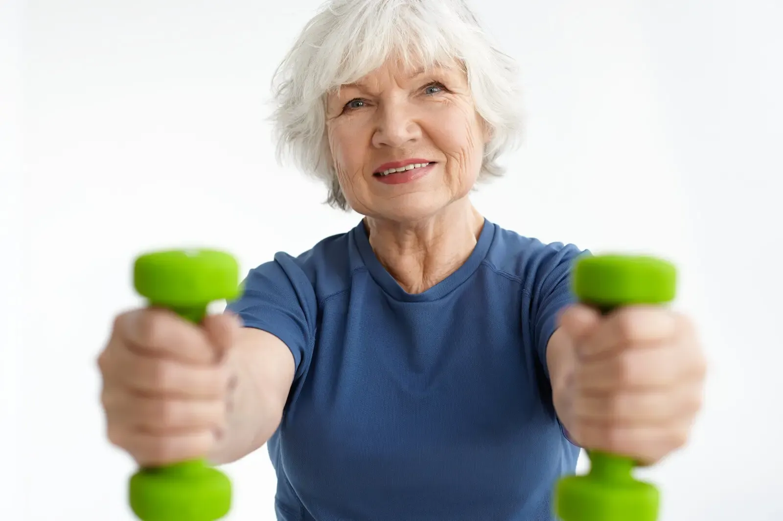 Older woman doing bicep curls with dumbbells in a gym